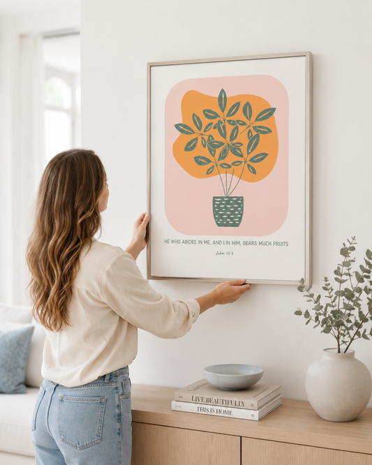 Woman hanging a framed John 15:5 print on a wall