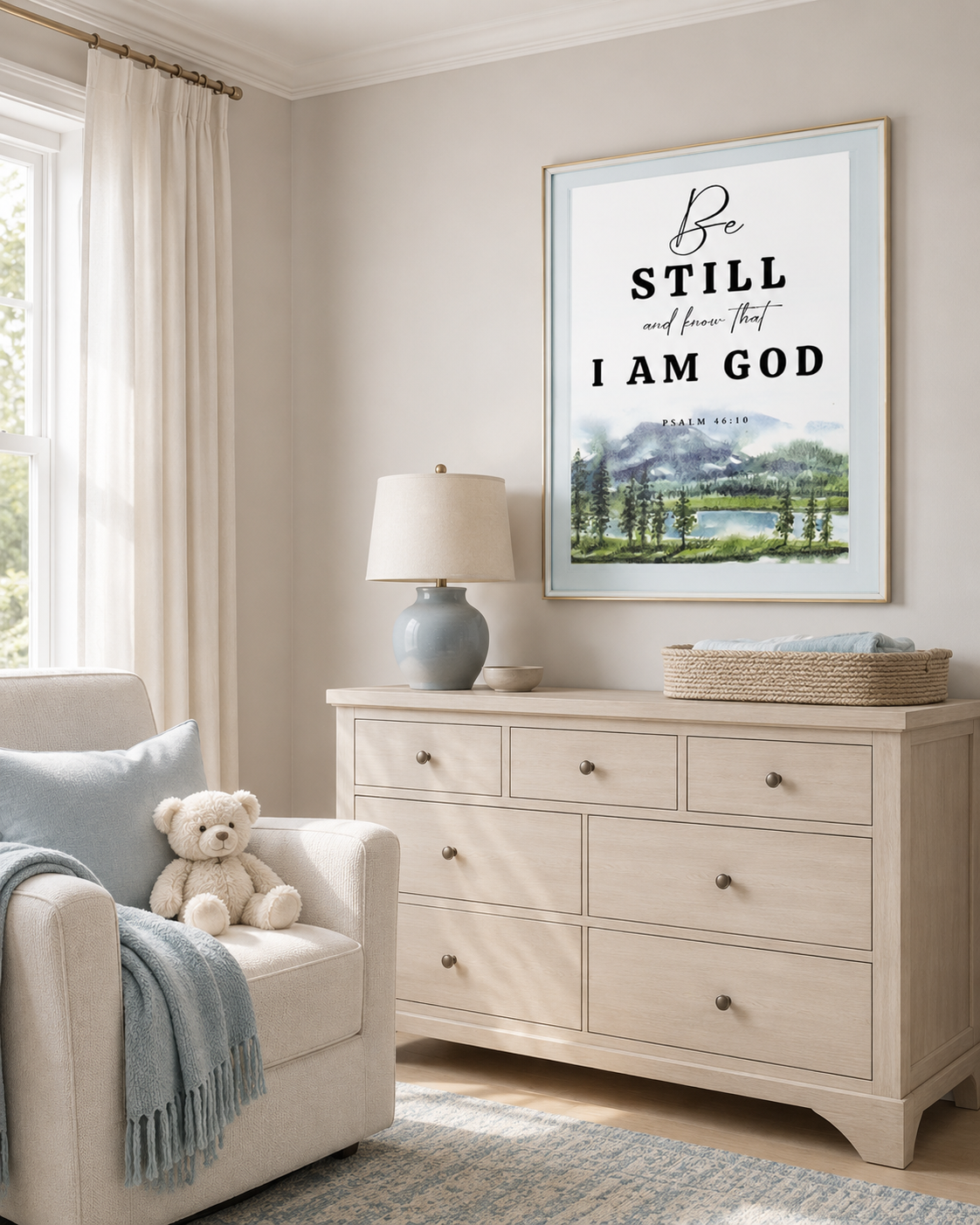 Psalm 46:10 wall art print in a gold-toned wood frame above a cream nursery dresser, with a white armchair, blue lamp, and soft teddy bear in a warm sunlit nursery.
