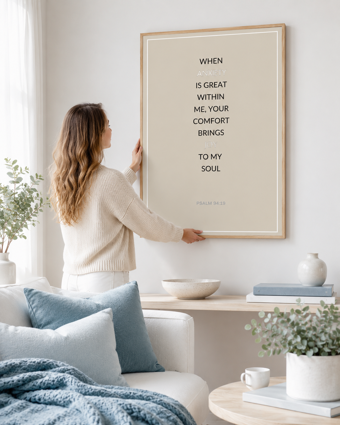 Woman placing framed Psalm 94:19 Bible verse art on a bedroom wall
