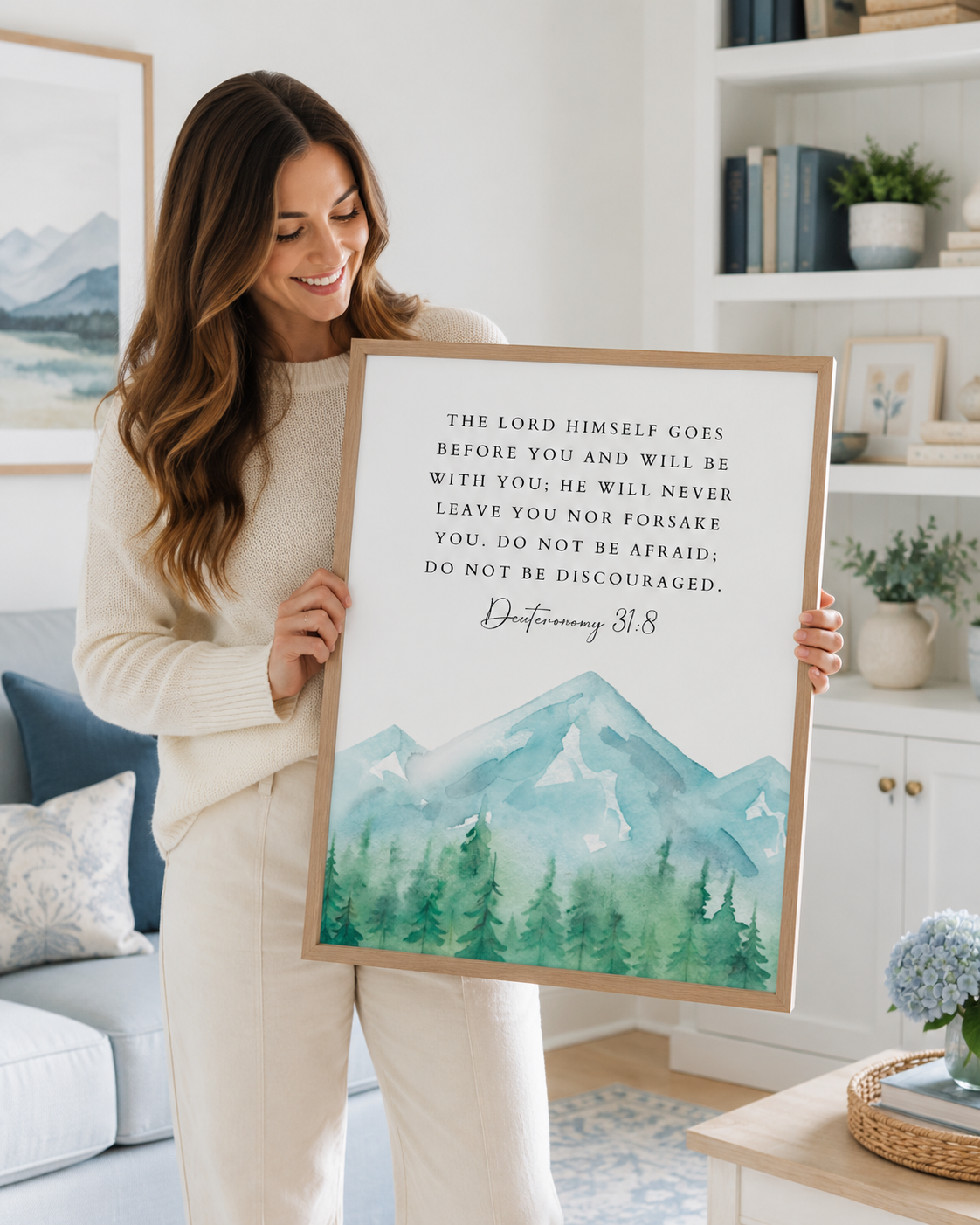 Woman holding a framed Deuteronomy 31:8 Bible verse print at home