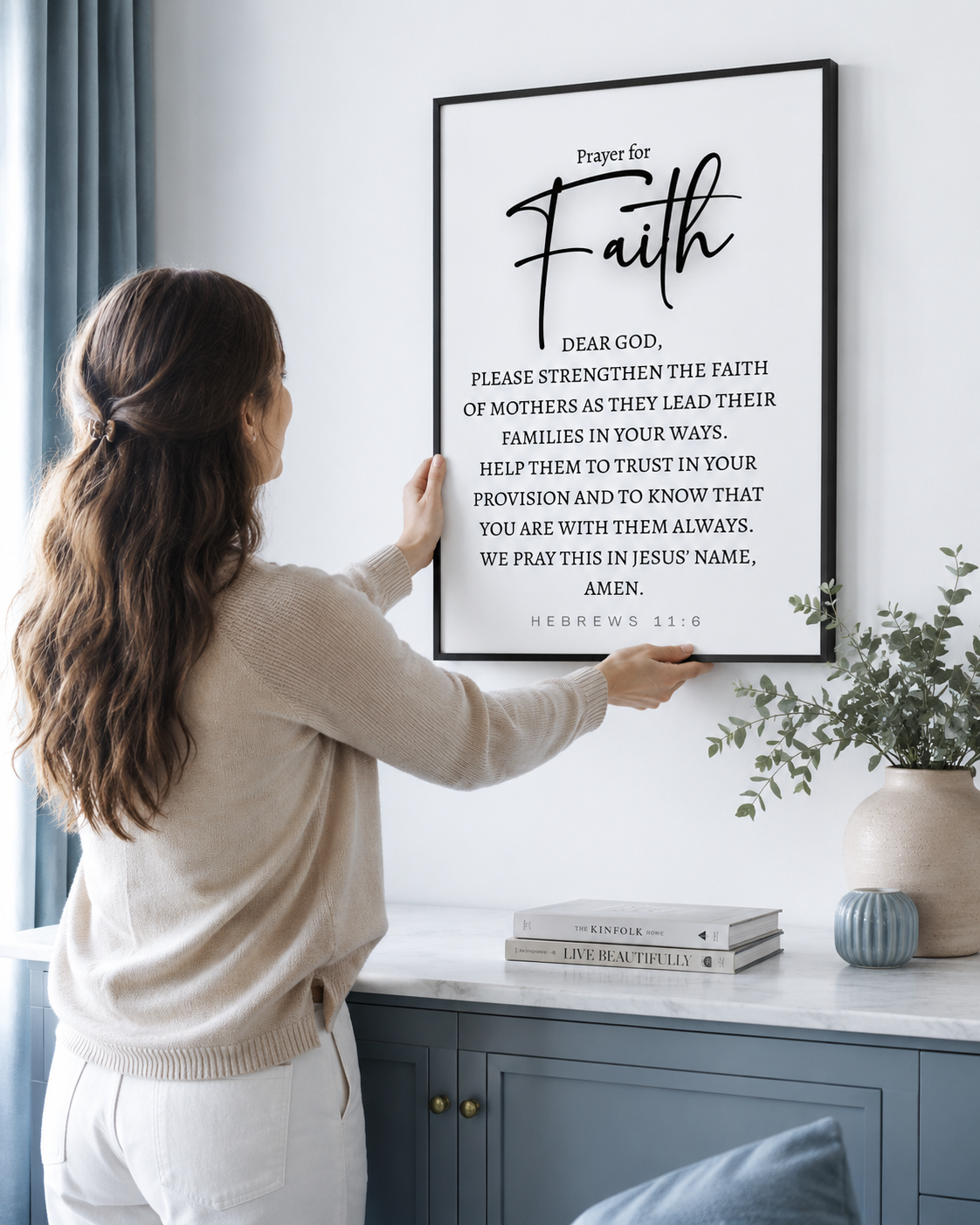 Woman hanging a framed Hebrews 11:6 prayer print on a wall