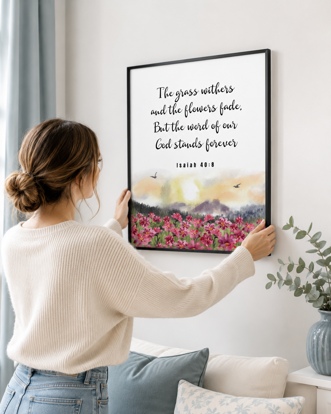 Woman hanging a framed Isaiah 40:8 print on a wall