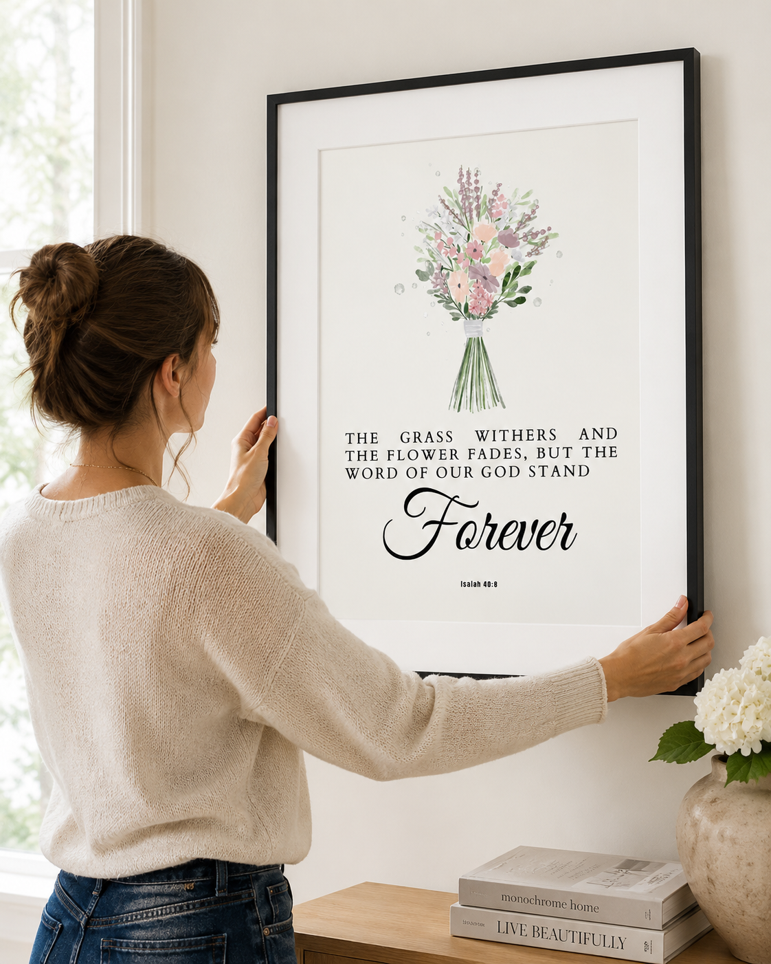 Woman hanging a framed Isaiah 40:8 "stands forever" print on a wall