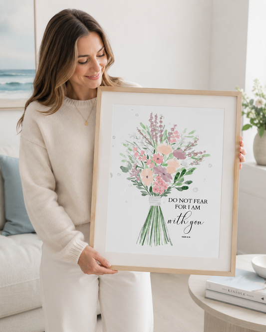 Woman holding a framed Isaiah 41:10 Bible verse print at home
