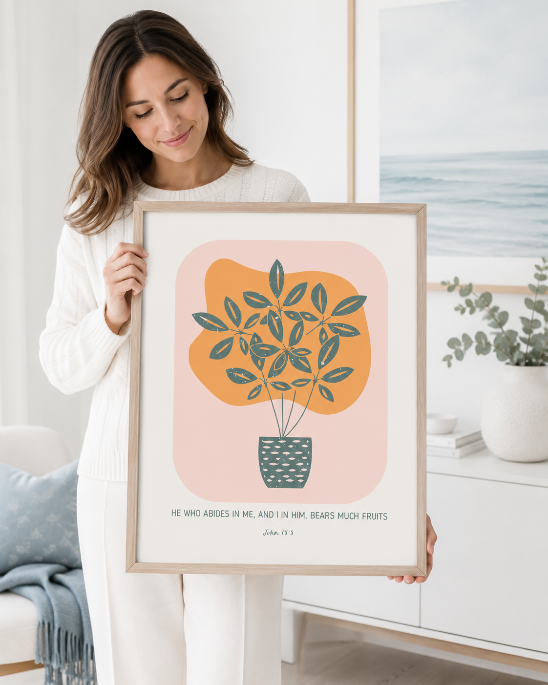 Woman holding a framed John 15:5 "Abide in Me" Bible verse print at home
