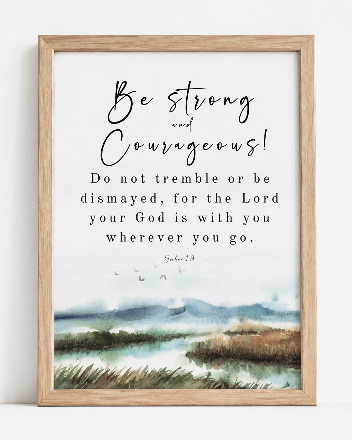Joshua 1:9 wall art print in a gold frame, showing "Be Strong and Courageous" scripture with watercolor landscape design