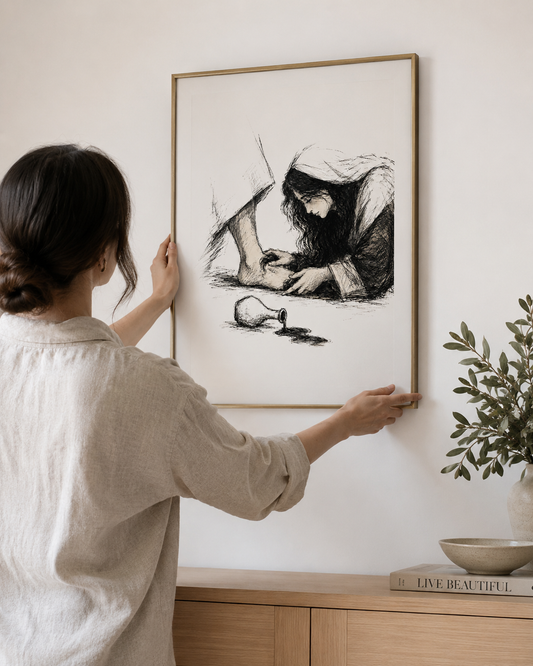 Woman hanging the framed Mary anoints Jesus ink sketch of hands and spilled perfume jar