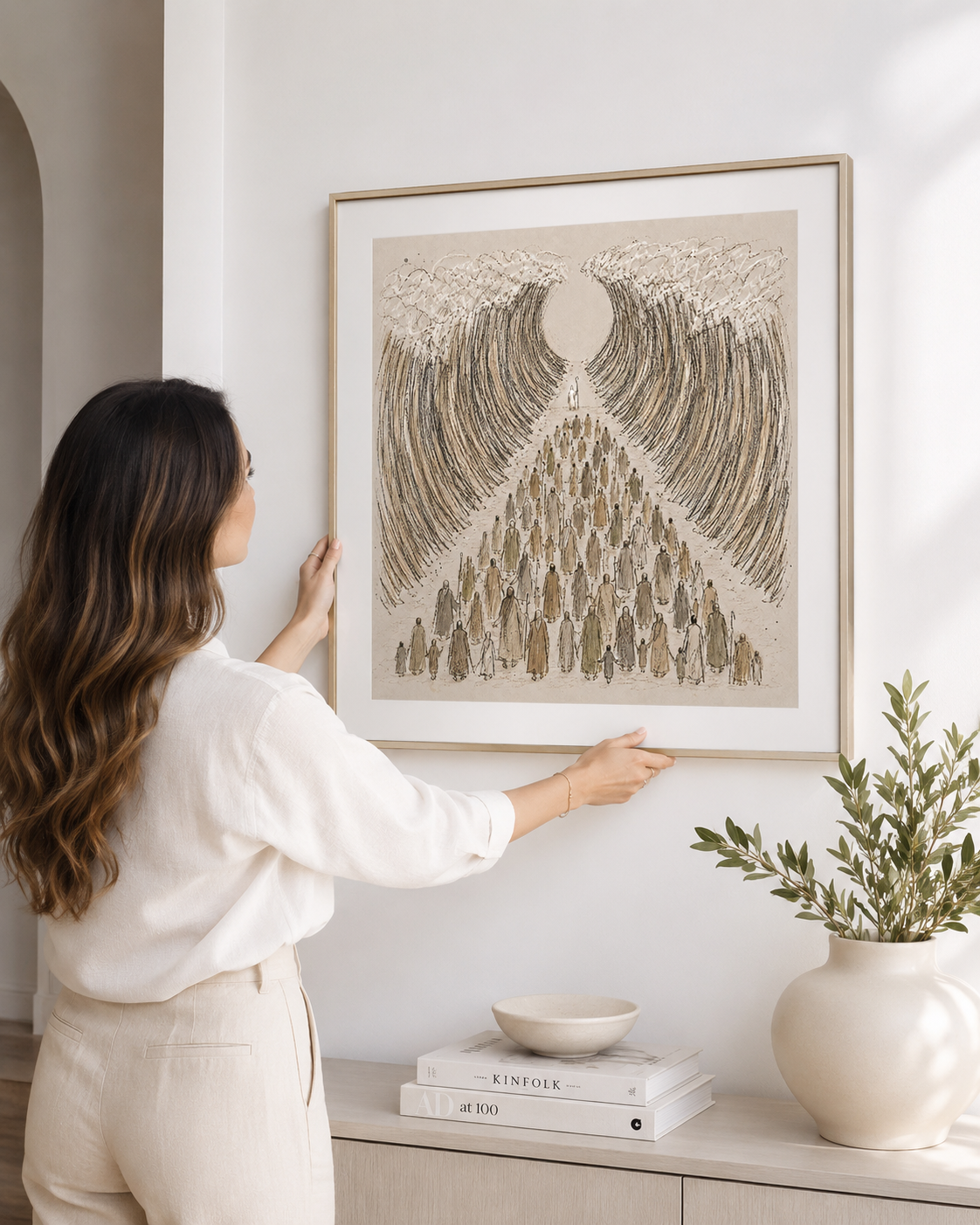 Woman hanging a framed Moses parts the Red Sea print on a wall