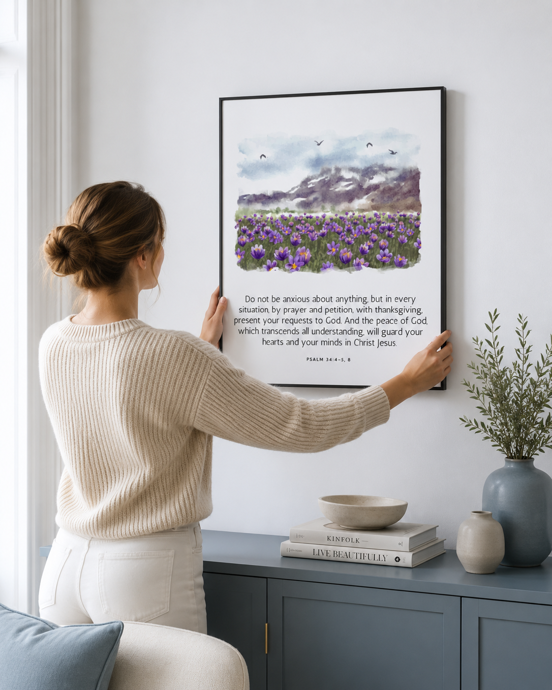 Woman hanging a framed Philippians 4:6-7 print on a wall
