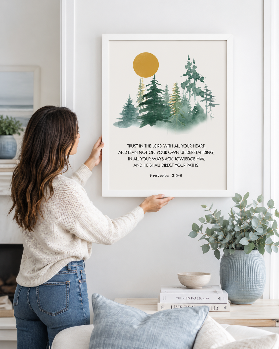 Woman hanging a framed Proverbs 3:5-6 "Trust in the Lord" print on a wall
