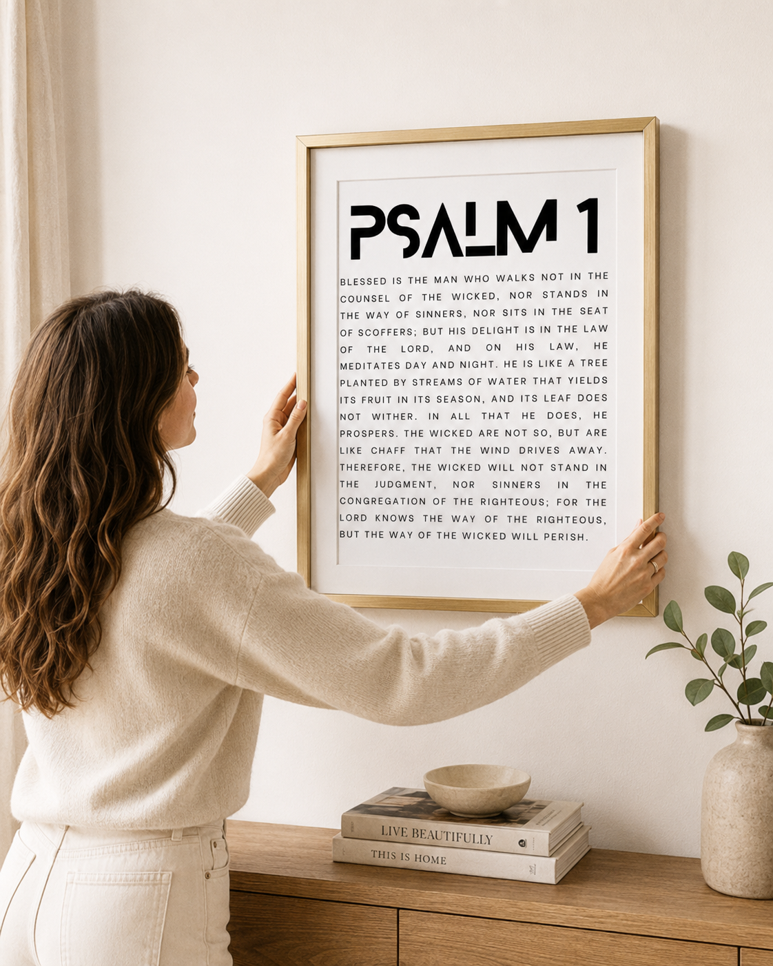 Woman hanging a framed Psalm 1 print on a wall