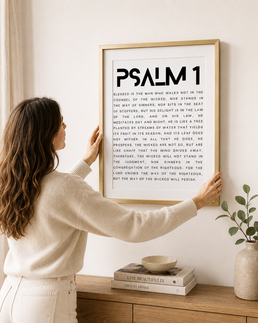 Woman hanging a framed Psalm 1 print on a wall