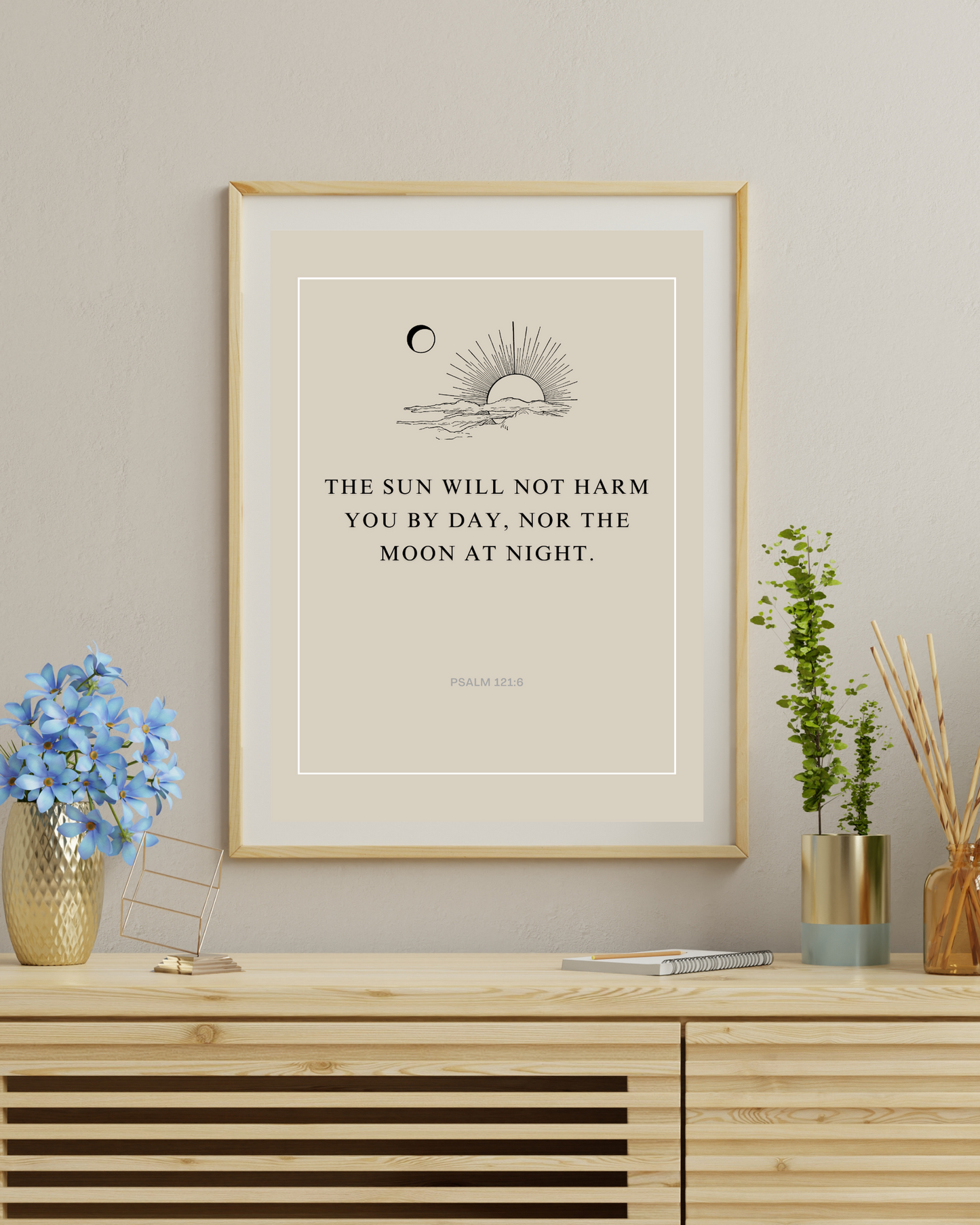 Wood-framed Psalm 121:6 wall art print with minimalist sun and moon line art, displayed above a sofa in a living room
