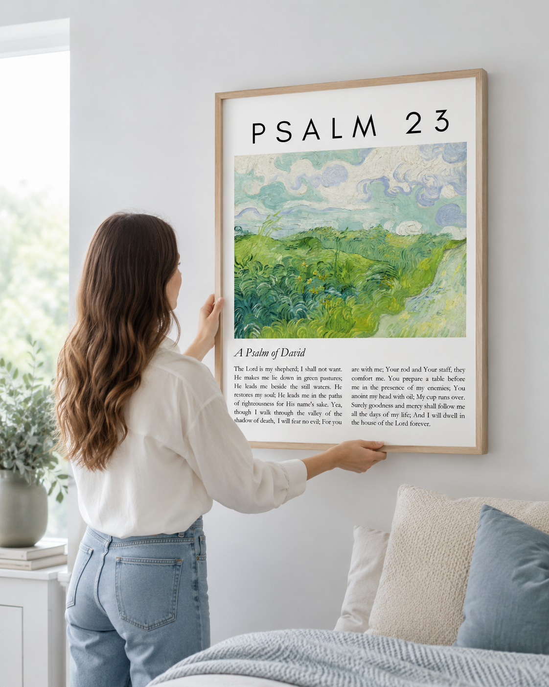 Woman hanging a framed Psalm 23:1-4 green pastures print on a wall