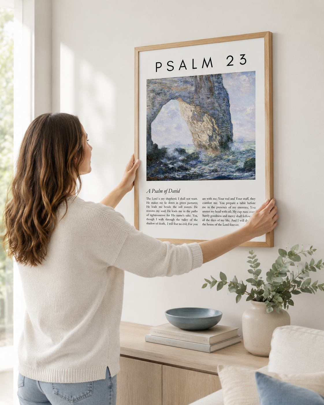 Woman hanging a framed Psalm 23 wall art print on a wall