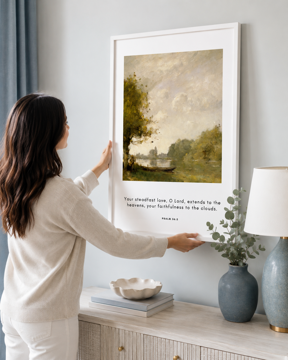Woman hanging a framed Psalm 36:5 print on a wall