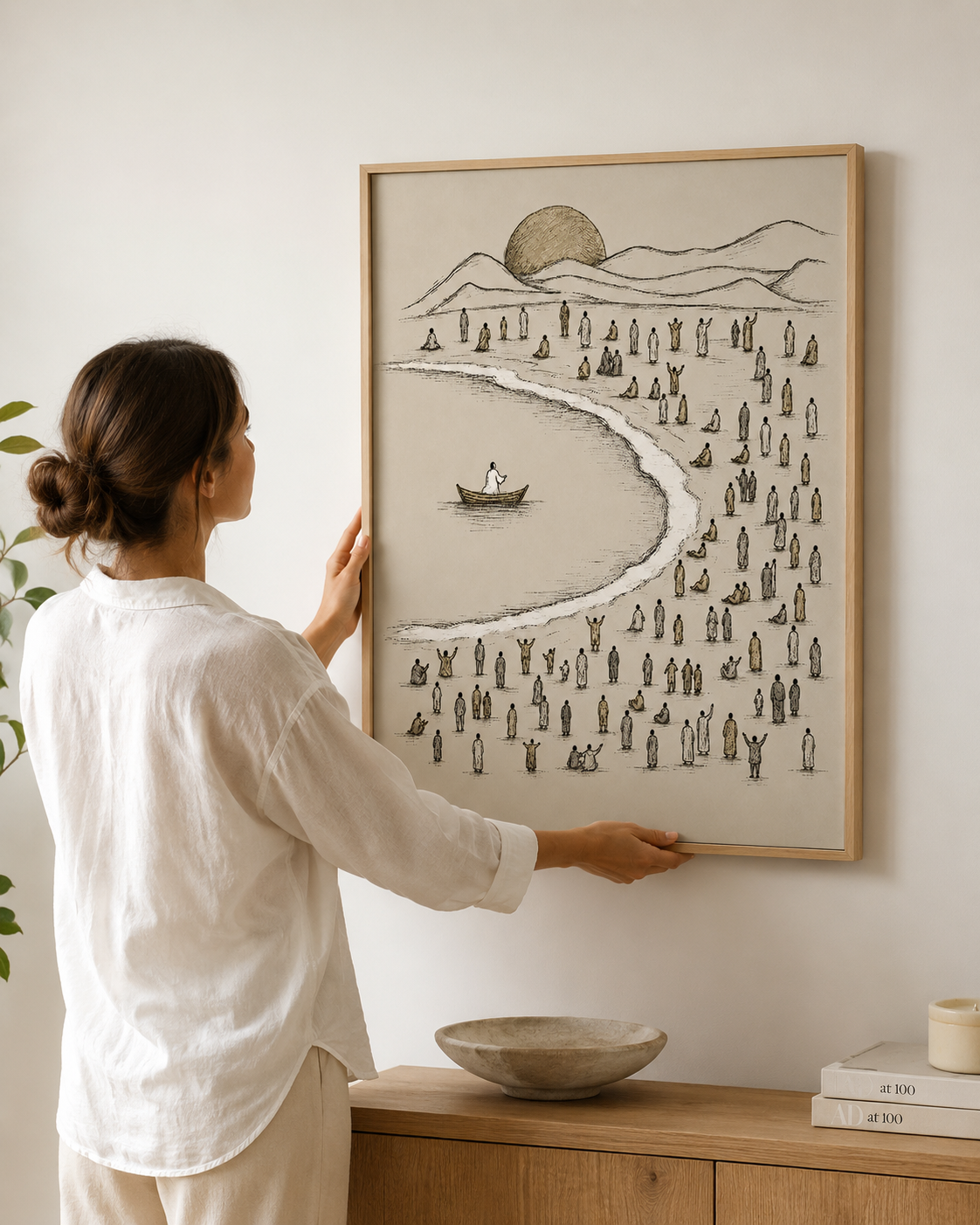 Woman hanging a framed Jesus teaching from the boat print on the wall
