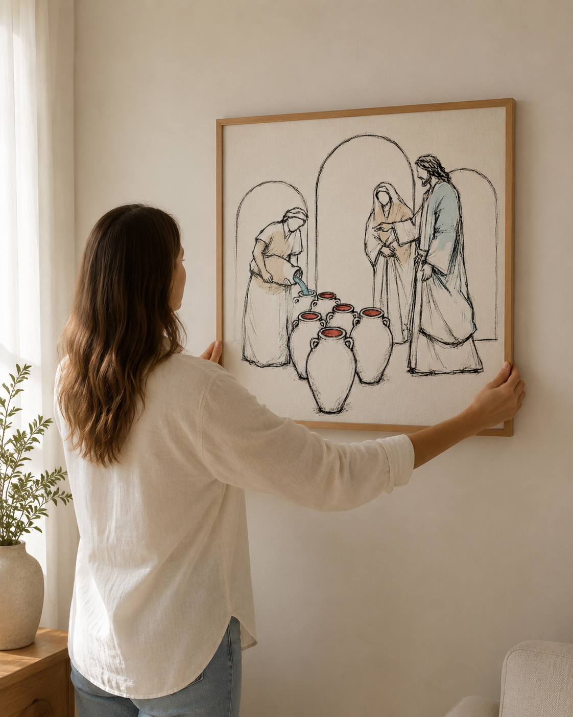 Woman hanging a framed Jesus turns water into wine bible sketch on the wall