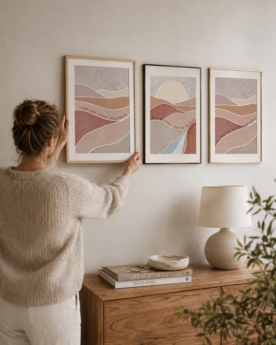 Woman hanging a Faith Can Move Mountains framed triptych in a bedroom